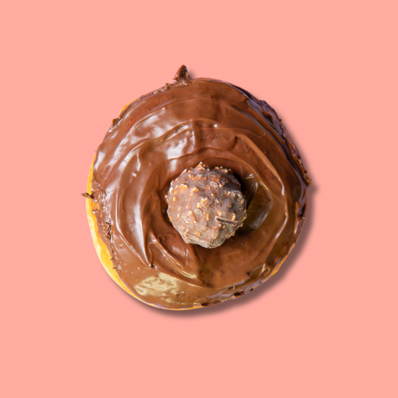 Top-down view of Ferrero chocolate donut with hazelnut topping on pink background – Go Nuts Donuts Nairobi